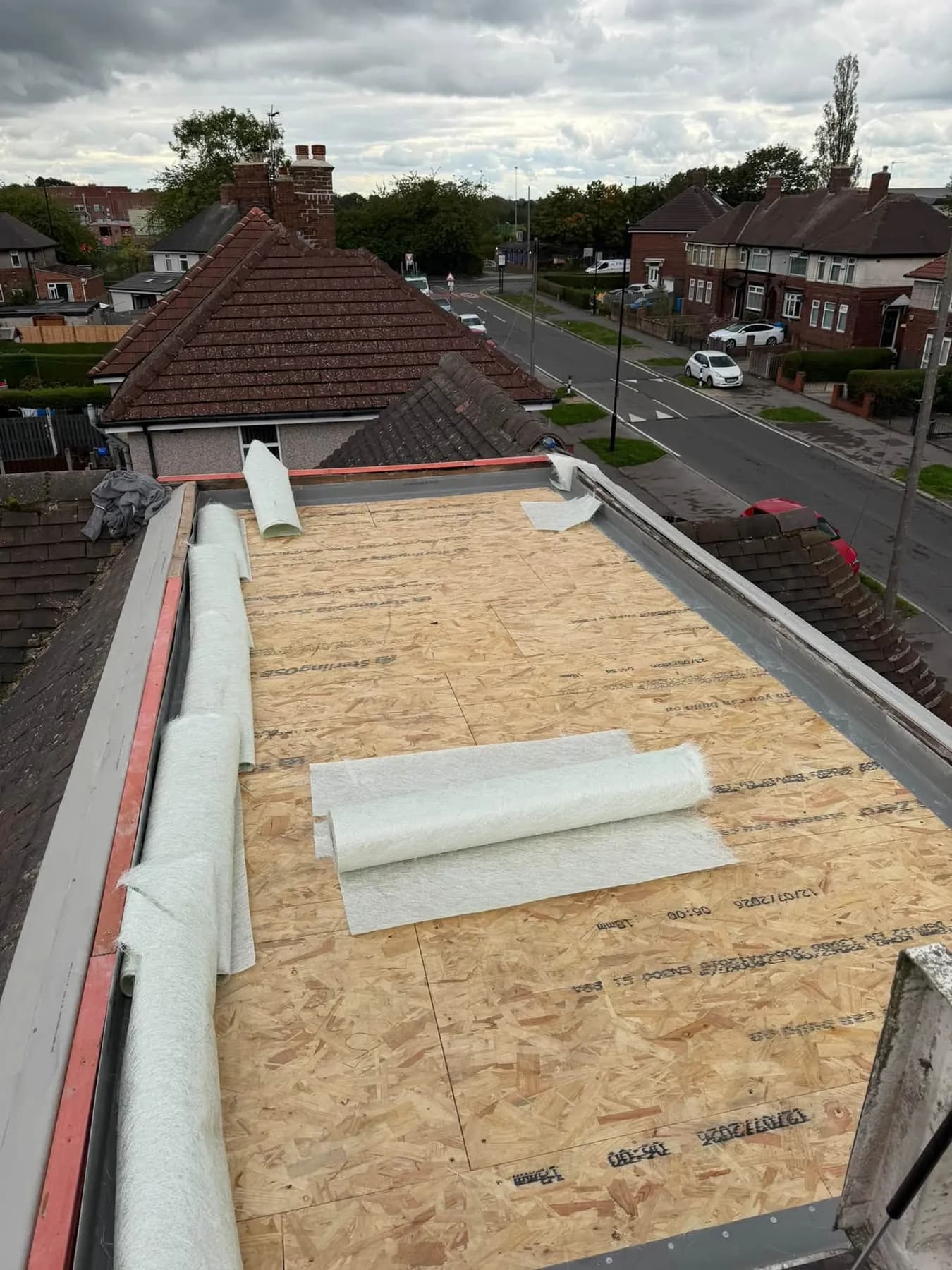 A new timber deck laid on a flat roof, with rolls of fibreglass matting ready to go on
